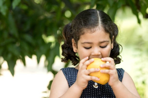 Indian girl eating mango fruit